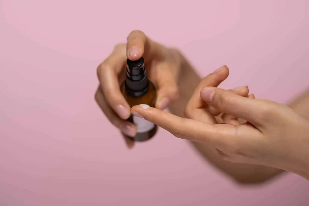 Woman applying gel serum to her finger from a brown dropper bottle
