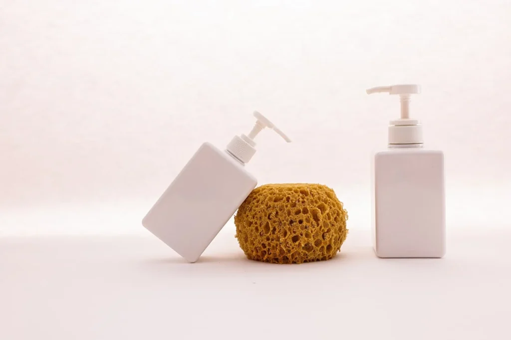 Cleansing sponge next to two bottles of liquid soap